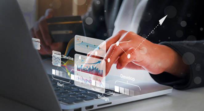 Close-up of a person's hands using a laptop, credit card, and interactive financial data displayed on the screen, representing online banking, financial technology, and digital transactions.