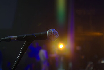 A microphone is pointed at a bright light. The microphone is black and silver. The light is yellow and orange