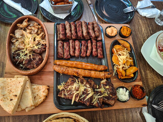 Varieties of sausages and meats along with various seasonings placed on a wooden base. Top view photo.