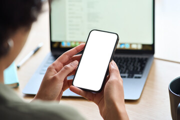 Over shoulder view of Afro woman student holding mobile phone with white blank mock up cellular screen applications working elearning using smartphone. Cellphone display mock up for advertising.