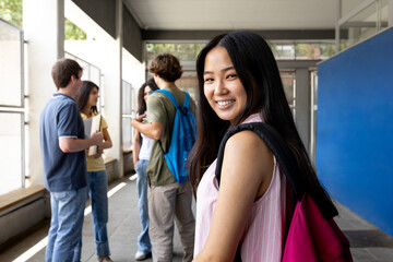 Happy asian student smiling in university hallway with friends