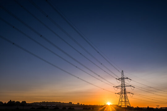 Electricity pylons and high voltage power lines at sunrise in countryside