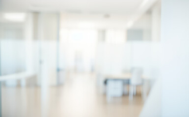 Blurred office interior with desks and partitions in a bright white space.