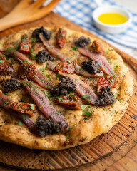 Authentic Italian focaccia with salted anchovies, sun-dried tomatoes, and black olives.