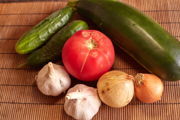 Fresh vegetables on the table. garlic, tomato, zucchini onion, marrow, potatoes, cucumber.