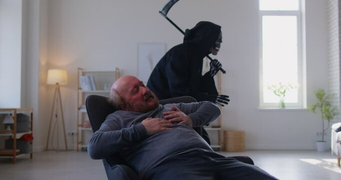 Senior man on chair clutching chest in pain, experiencing heart attack or infarct and feeling proximity of death. Skeleton in grim reaper death costume with scythe sneaking around on background.