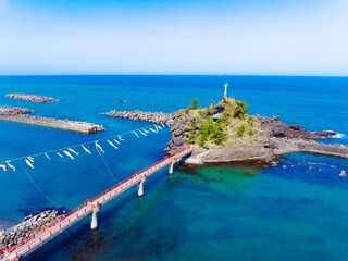 糸魚川市能生の弁天岩と青い海、空に舞う鯉のぼり｜5月の空撮風景