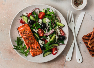 Delicious balanced lunch - greek salad and baked salmon on a light background, top view