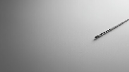 overhead shot of solitary paintbrush resting on pristine white canvas offering ample copy space