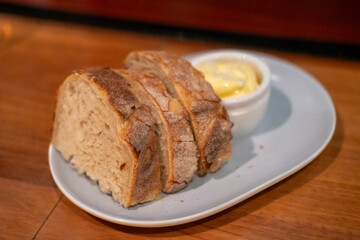 Sliced bread with butter served on plate, on the table in the restaurant