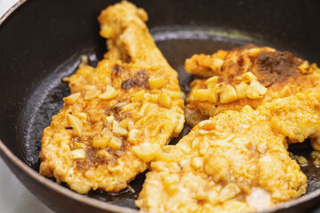Chicken breast pieces frying in garlic dressing on a skillet, capturing a flavorful and healthy cooking process