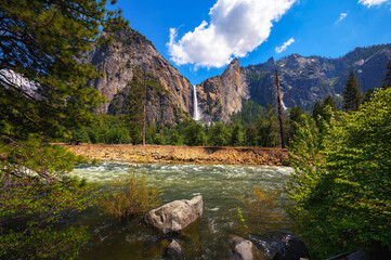 Bridalveil Fall cascading into Yosemite Valley with the Merced River in the foreground in Yosemite National Park, California.