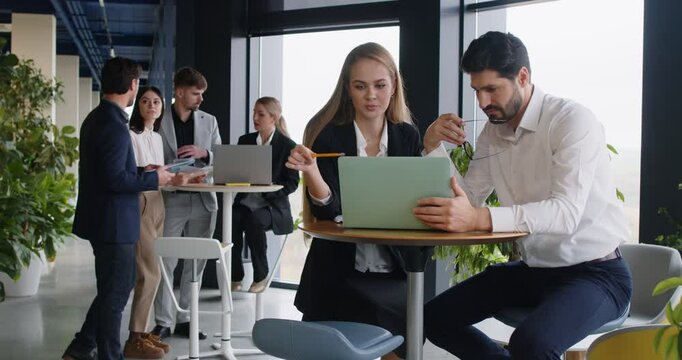 Colleagues collaborating together in the office, using a laptop during a business meeting. The discussion focuses on accounting and teamwork, emphasizing efficient working methods and communication.