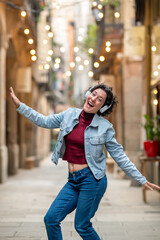 Carefree young woman dancing and listening to music in a city street