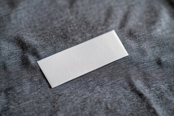 Blank white rectangular tag on gray fabric
