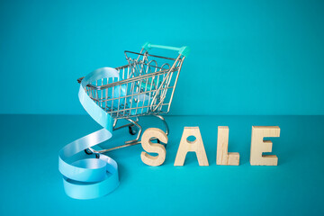 Mini shopping cart with blue ribbon and wooden letters forming 