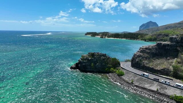 Scenic aerial showing the winding Maconde coastal road with turquoise ocean and iconic Le Morne Brabant mountain in the background, southern Mauritius