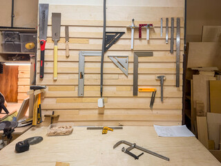 Close-up of workshop tool wall featuring screwdriver, ruler, clamp, wrench, pliers, and precision carpentry gear for skilled work.