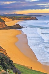 Golden sands meet turquoise waves along a dramatic coastline, framed by lush green cliffs under a vibrant sky