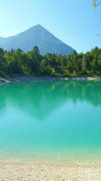 Turquoise waters of Urisee shimmering under the alpine sun, surrounded by forests and peaceful mountain views in Tirol
