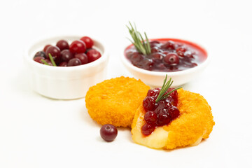 Camembert cheese fried in breading with cranberry sauce on white background