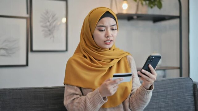 A young woman texting on her mobile phone holding a card