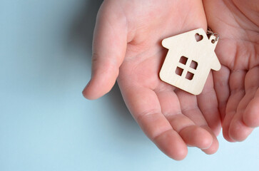 A keychain in the shape of a house lies in the hands. Blue background.