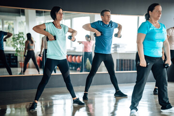 Fototapeta premium Multiethnic fitness enthusiasts lifting dumbbells in sync. Focus on wellness, teamwork, and strength