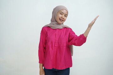 Smiling Young Asian Woman in Hijab Gesturing Upward with Open Hand isolated on White Background