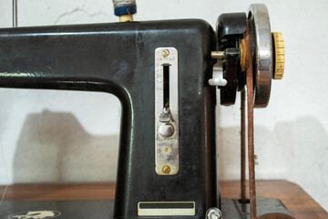 Side profile of an old black sewing machine placed on a wooden table, showcasing its retro design, faded paint, and robust construction—ideal for vintage and tool-themed visuals.