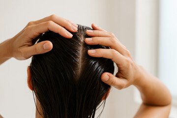 Naklejka premium Hair Care Routine: A close-up view of a person's hands gently massaging a scalp, with wet hair glistening, illustrating a daily beauty regimen, highlighting hair health, and skincare.
