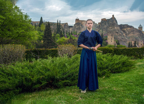 Young man in Japanese kimono  kendo fighter on stunning background  with fortress