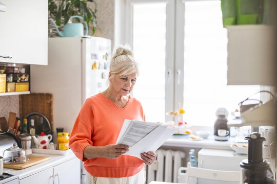 Senior woman looking through financial documents at home 

