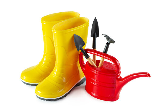 Yellow rubber boots, watering can and garden tools isolated on white background.