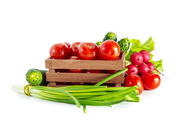 Tomatoes, radishes, green onions, cucumbers and lettuce in a wooden box. Isolated on white background.