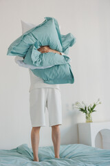 A person is joyfully holding a large and fluffy pile of colorful pillows high above their head, creating an amusing and playful scene