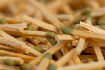 wooden matches with a green head scattered in a large pile, a large number of matches