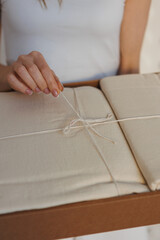 A woman is carefully tying a small piece of paper with a string, ensuring it is secure and neat for whatever purpose she has in mind
