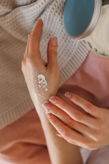 A woman is diligently applying lotion to her hand to keep her skin moisturized and healthy, promoting personal care practices