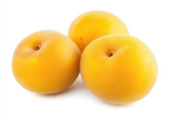Three ripe yellow plums arranged on a white surface, showcasing their smooth texture
