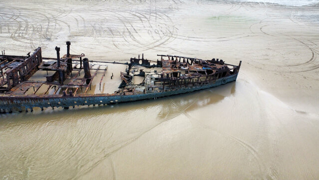 A washed up shipwreck on a sandy beach, seen from above