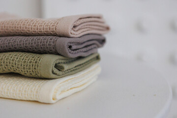 On a table, there are three cozy blankets that are neatly stacked on top of one another, creating a warm and inviting appearance