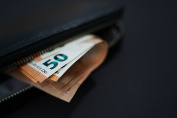black wallet with 50 euro banknotes on black background.Finance and spending concept.