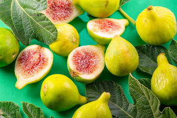 Ripe green fig fruits with fig leaves and fig pieces isolated on green background.