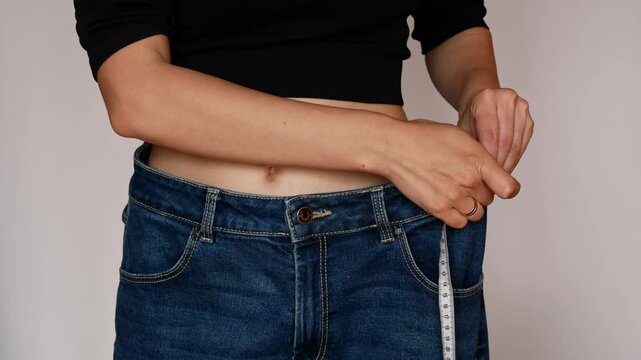  Slimming results, an athletic woman with a flat belly appreciates the difference in her pant size.