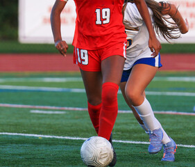 Obraz premium Female Soccer Player Running with the Ball being Chased by Competitor