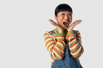 Screaming beautiful asian woman standing isolated on grey studio background.