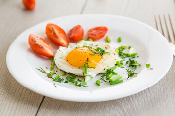 Fried eggs with cherry tomatoes and greens for breakfast