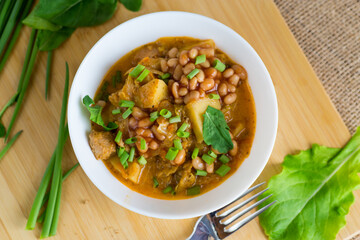 Fragrant stew with beans and vegetables served in a white bowl