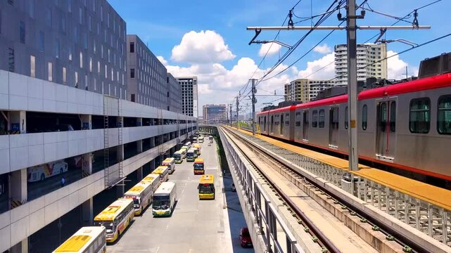Paranaque, Metro Manila - LRT-1 train heading to Dr. Santos runs on elevated guideway above buses and cars near PITX station. Public Transit in NCRv